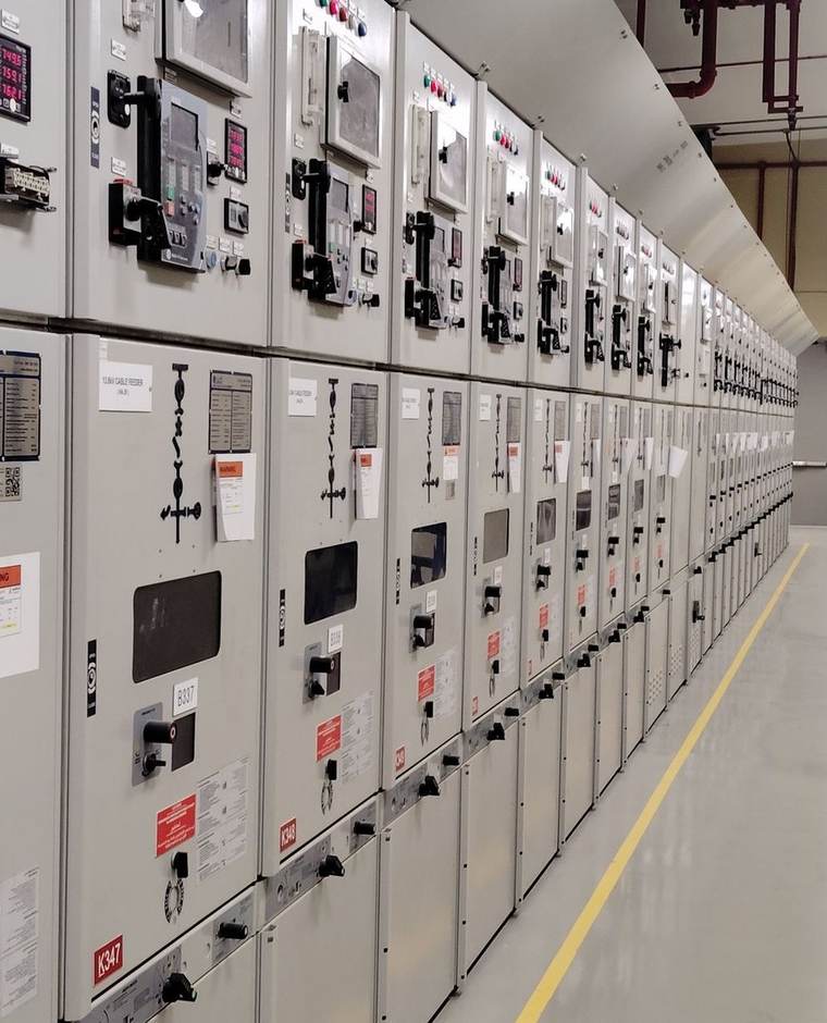 Salle de tableaux électriques industriels : rangée de cellules de distribution avec leurs appareils de protection et de mesure