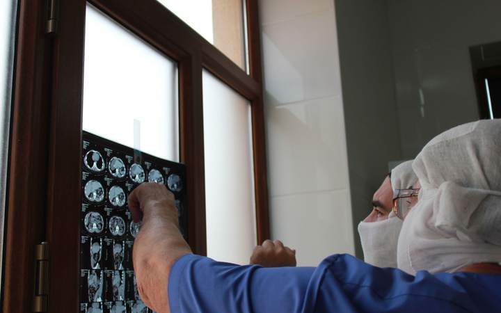 Soignante masquée examinant des clichés d’imagerie médicale posés contre une fenêtre