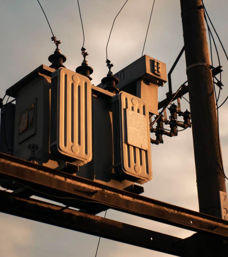 Transformateur électrique installé en haut d’un poteau, éclairé par la lumière du soir