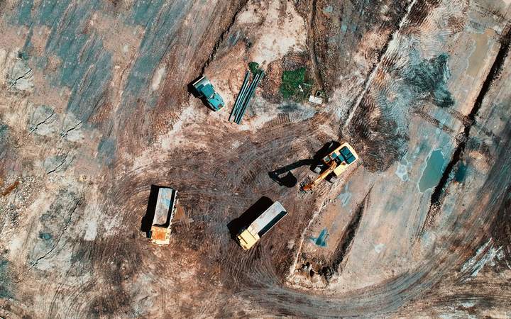 Vue aérienne d’un chantier de terrassement avec pelles et camions au fond d’une excavation