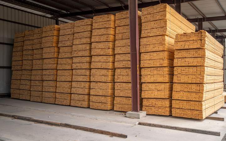 Paquets de planches de bois de sciage empilés sous un hangar à charpente métallique