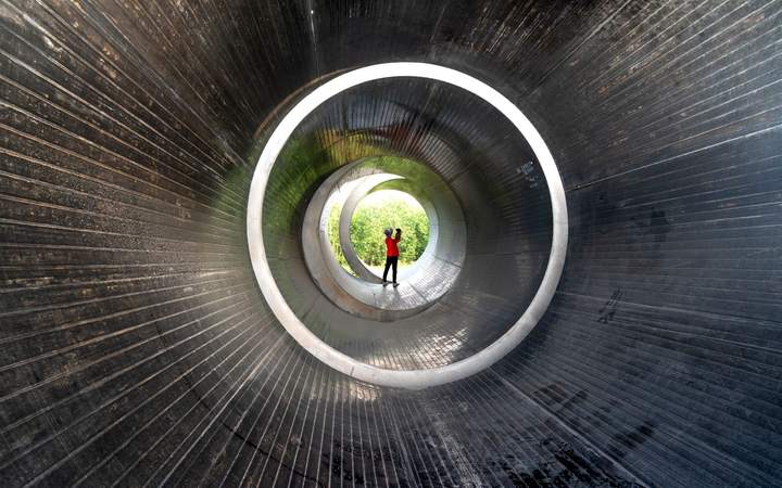 Galerie circulaire bétonnée en perspective avec un opérateur éclairé au fond du tunnel