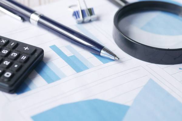 Calculatrice, stylo et loupe posés sur des graphiques financiers imprimés