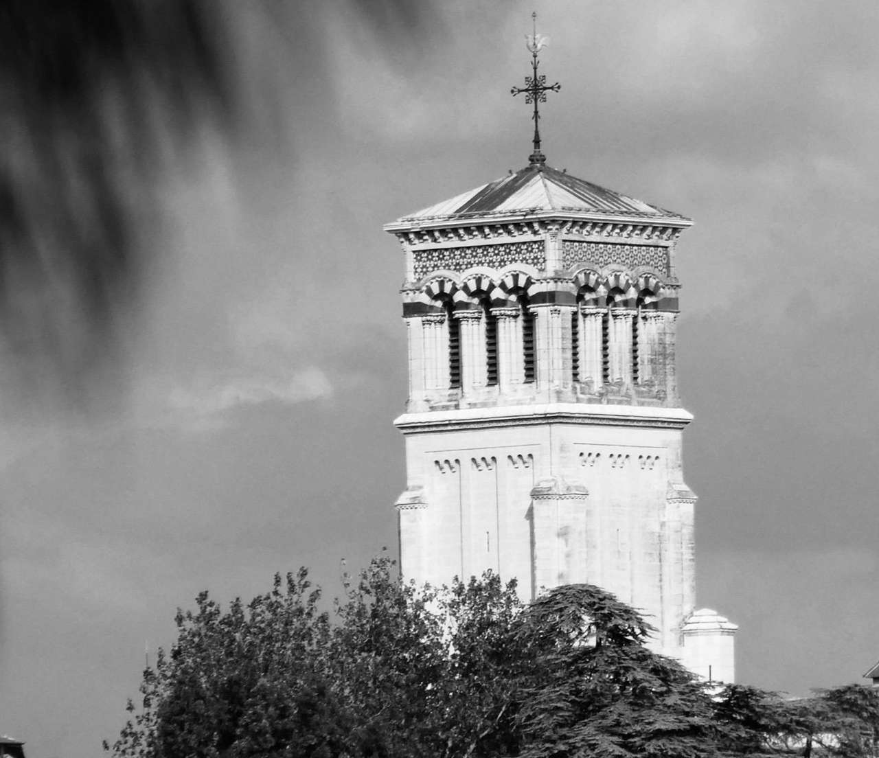 Clocher de style néo-roman émergeant des arbres à Valence, en noir et blanc