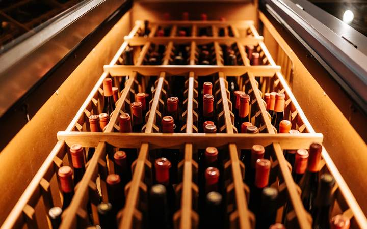 Casier en bois rempli de bouteilles de vin couchées dans une cave climatisée