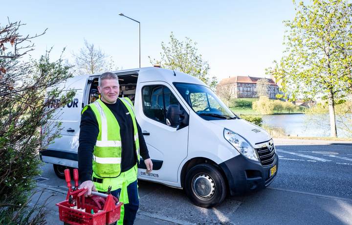 Artisan en gilet haute visibilité devant sa camionnette, caisse à outils à la main