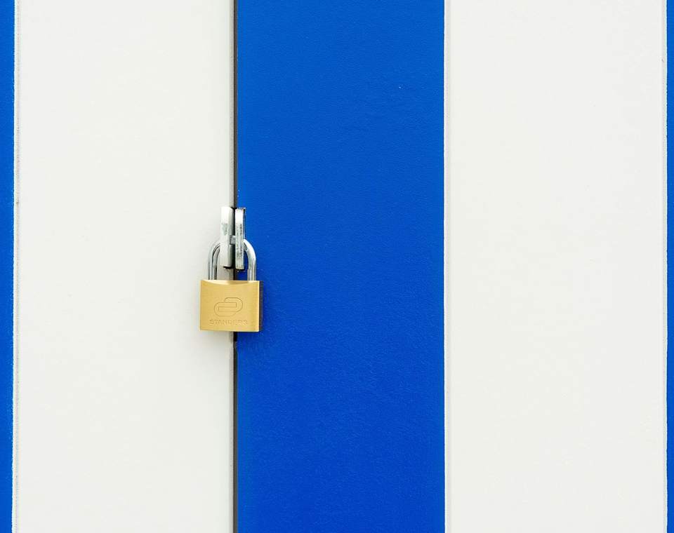 Cadenas fermé sur une porte de local technique bleue et blanche