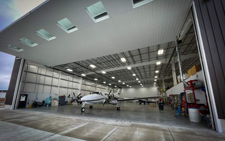Grand hangar aéronautique ouvert abritant un bimoteur à hélices