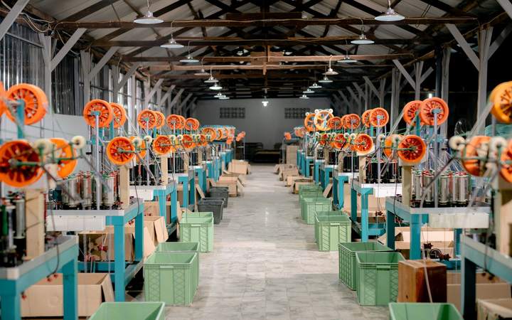 Atelier de tressage avec rangées de machines et bobines orange
