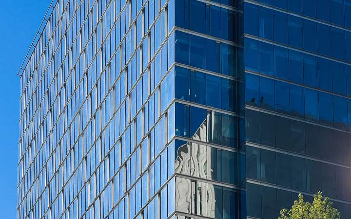 Façade en verre bleuté d’un immeuble de bureaux moderne reflétant le ciel