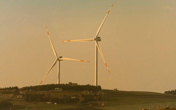 Deux éoliennes sur une colline au coucher du soleil