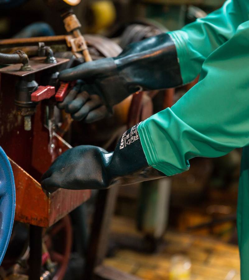 Opérateur en gants et tablier de protection manipulant une vanne sur une machine industrielle