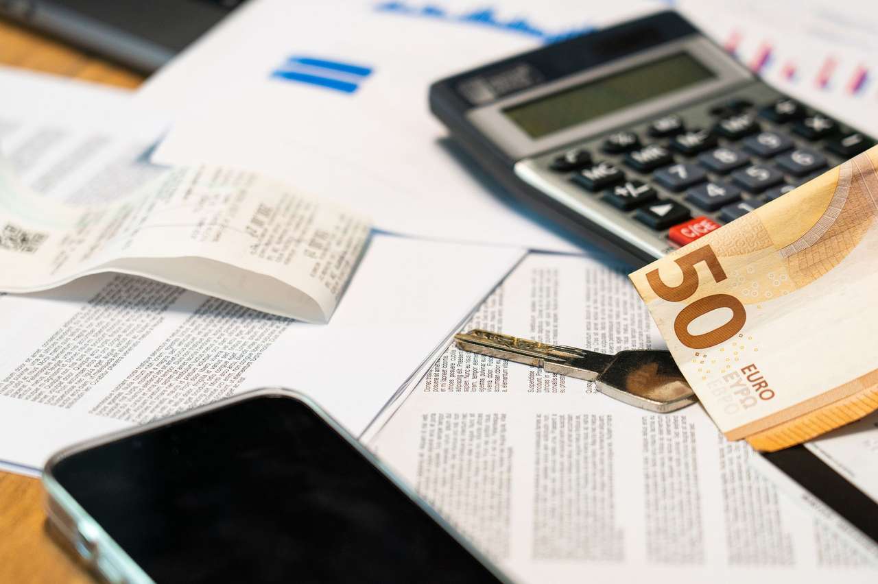 Calculatrice, billets en euros et documents imprimés étalés sur une table de travail