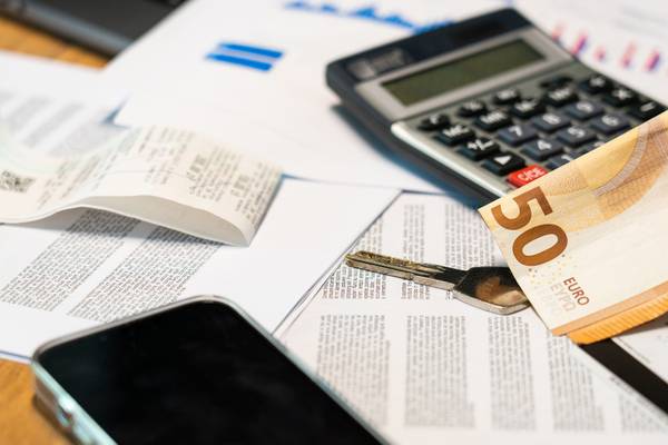 Calculatrice, billets en euros et documents imprimés étalés sur une table de travail