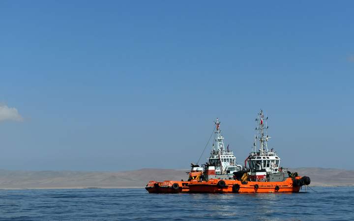 Deux remorqueurs orange en attente en pleine mer sous un ciel bleu