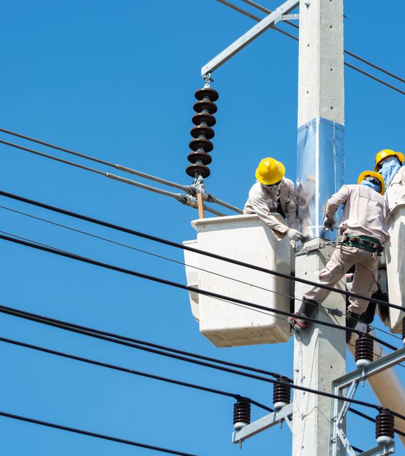 Deux techniciens en nacelle travaillant sur une ligne électrique aérienne équipée d’isolateurs