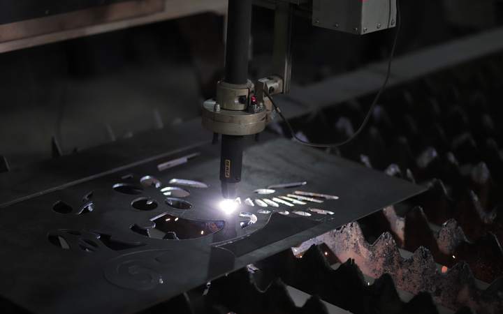 Tête de découpe laser projetant des étincelles sur une tôle d’acier