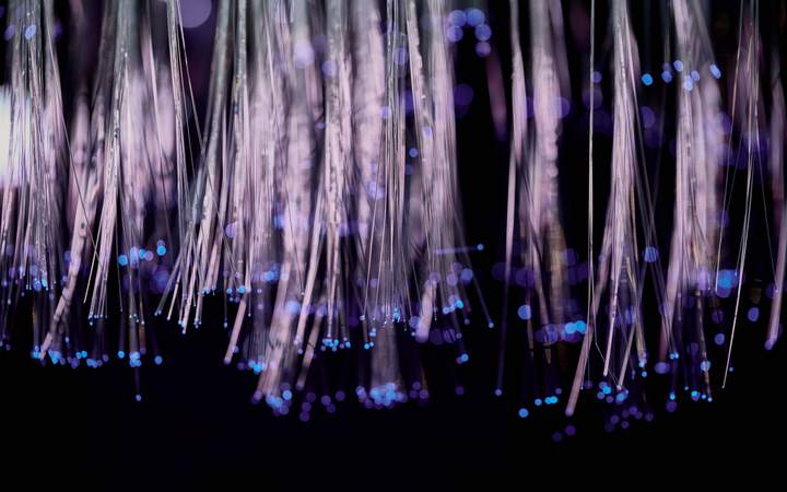 Faisceau de fibres optiques lumineuses suspendues sur fond sombre