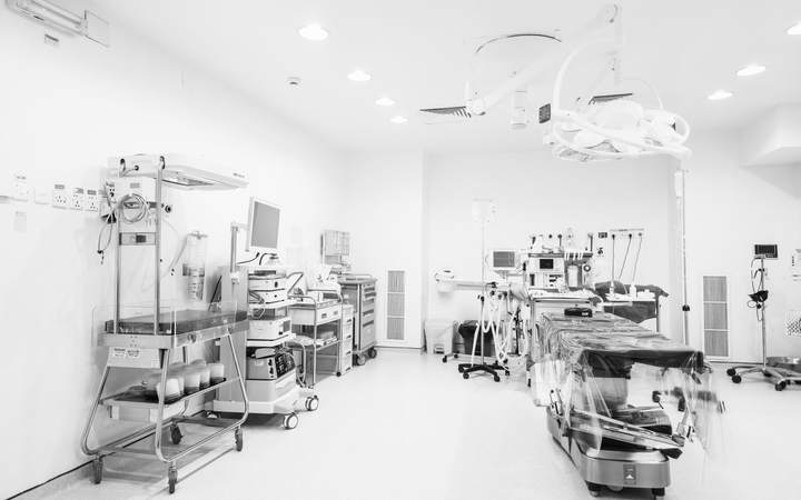 Bloc opératoire blanc équipé de scialytiques et de colonnes techniques