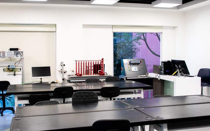 Salle de laboratoire lumineuse avec paillasses noires, écrans et équipements scientifiques