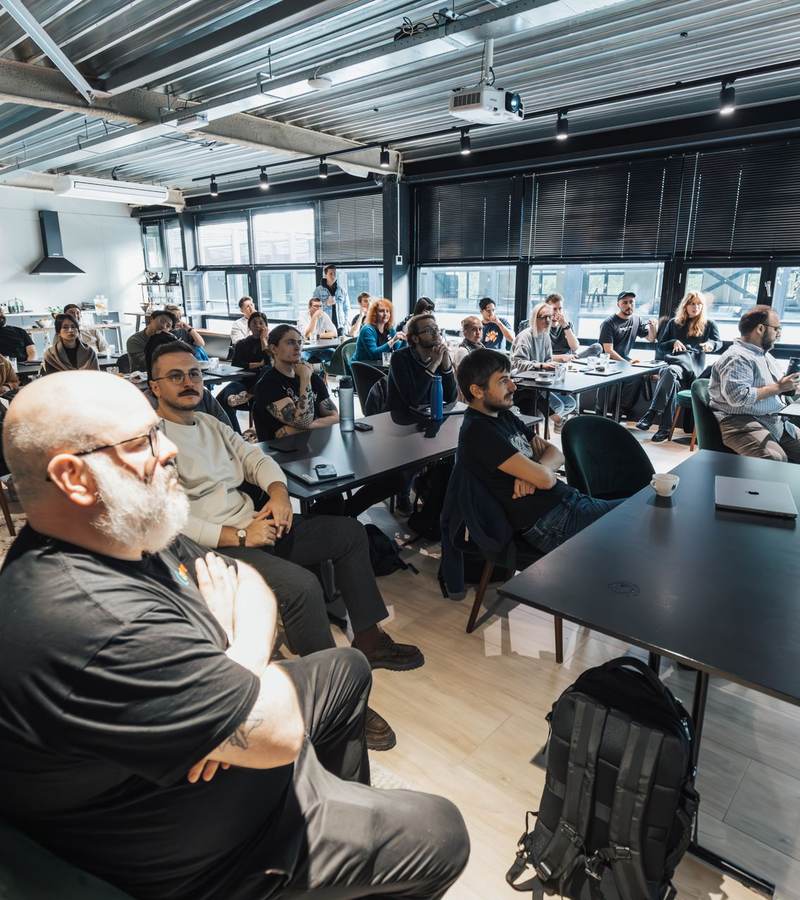 Nombreux participants assis écoutant une présentation dans une grande salle de formation lumineuse