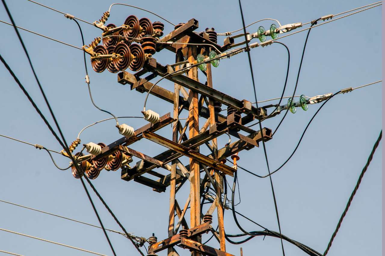 Poteau de ligne électrique aérienne avec ses isolateurs et ses conducteurs sous un ciel bleu