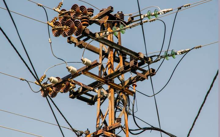 Poteau de ligne électrique aérienne avec ses isolateurs et ses conducteurs sous un ciel bleu