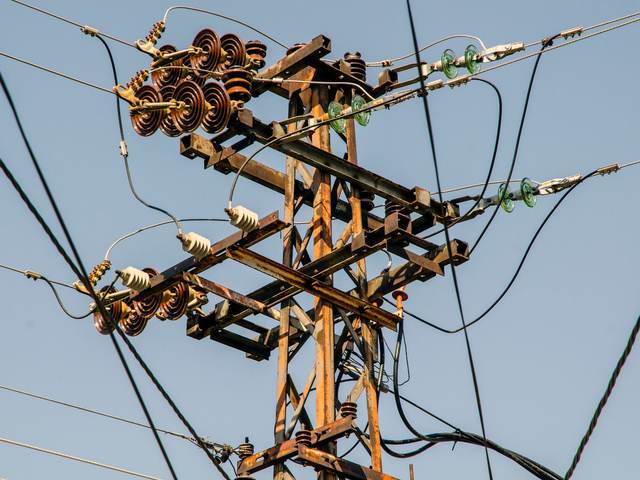 Poteau de ligne électrique aérienne avec ses isolateurs et ses conducteurs sous un ciel bleu