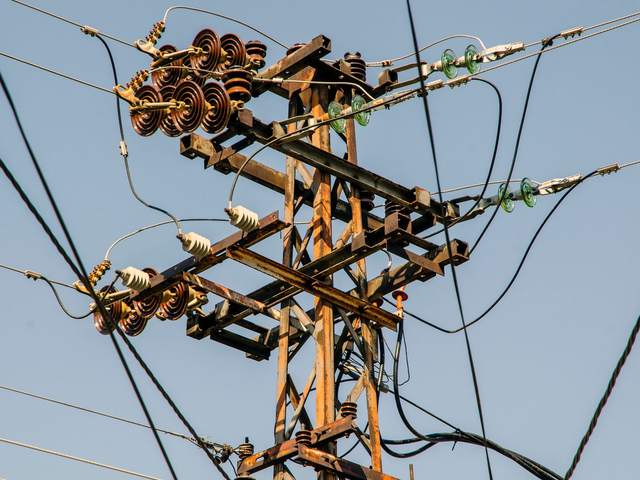 Poteau de ligne électrique aérienne avec ses isolateurs et ses conducteurs sous un ciel bleu