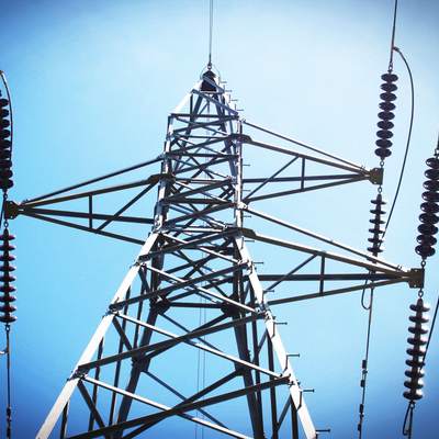 Pylône de ligne haute tension et chaînes d’isolateurs vus en contre-plongée sur ciel bleu