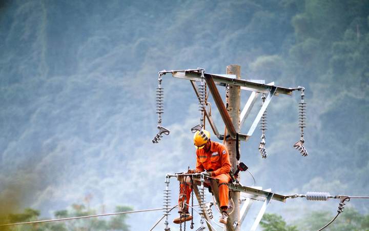 Monteur de lignes intervenant en hauteur sur un poteau de réseau électrique