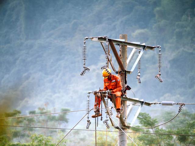Monteur de lignes intervenant en hauteur sur un poteau de réseau électrique