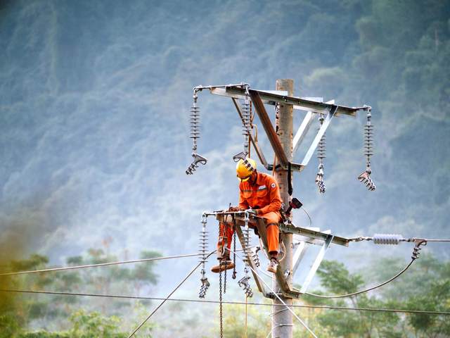 Monteur de lignes intervenant en hauteur sur un poteau de réseau électrique