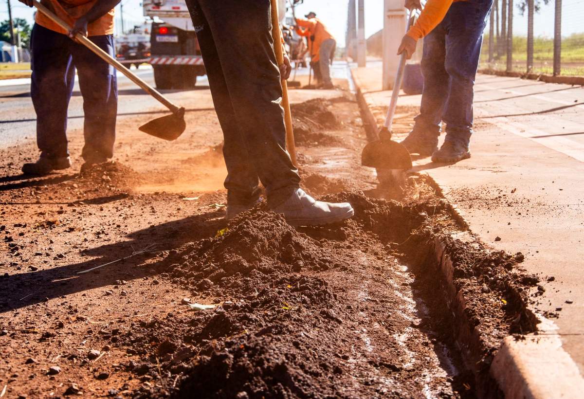Ouvriers en tenue de chantier creusant une tranchée à la pelle, en lumière de fin de journée