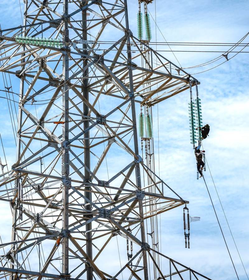 Pylône haute tension en treillis métallique avec deux techniciens encordés sur la structure