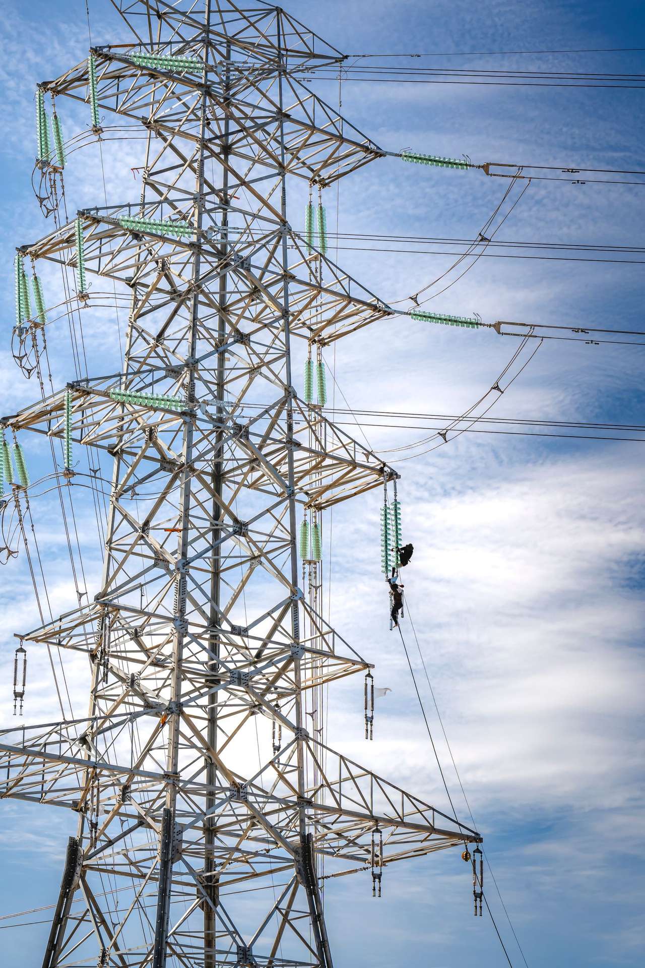 Pylône et lignes haute tension avec un technicien en ascension