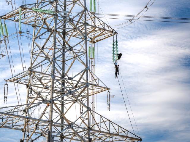 Pylône et lignes haute tension avec un technicien en ascension