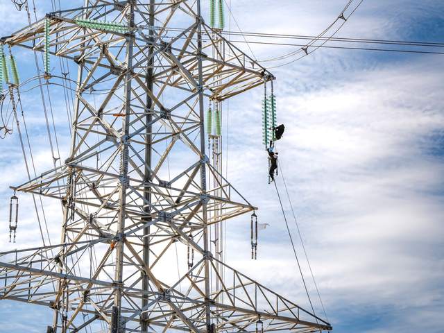 Pylône et lignes haute tension avec un technicien en ascension