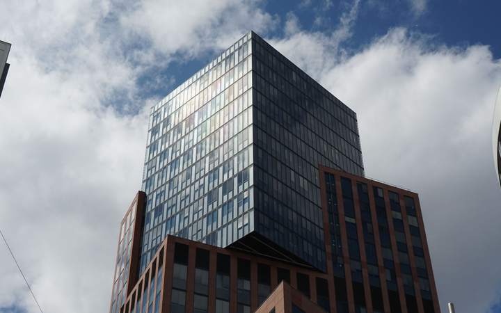 Immeuble de bureaux aux façades vitrées et briques sombres vu en contre-plongée