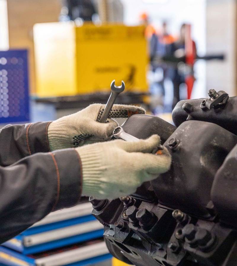 Mains gantées serrant un écrou à la clé plate sur un moteur en atelier de maintenance