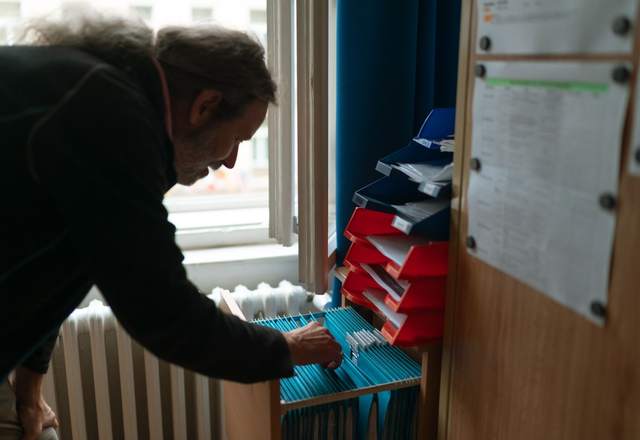 Agent triant le courrier dans des casiers de rangement d’un bureau administratif