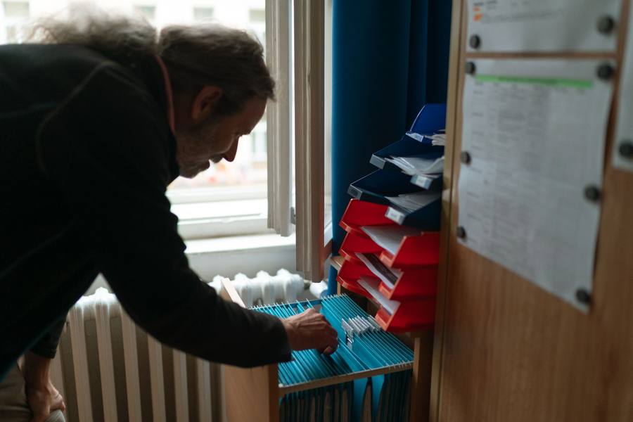 Agent triant le courrier dans des casiers de rangement d’un bureau administratif