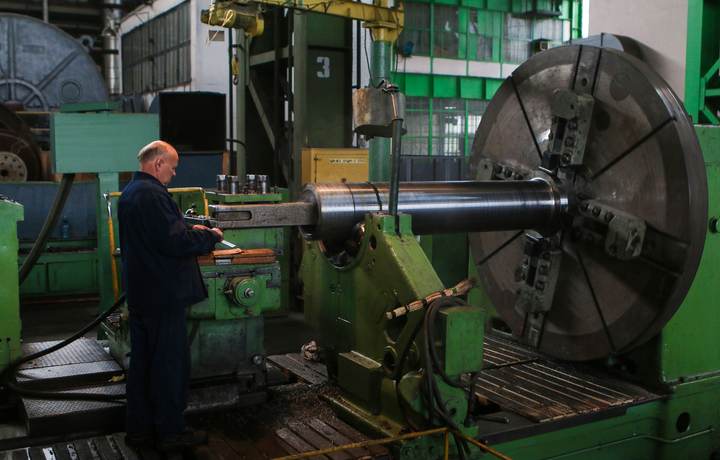 Tourneur au travail sur un grand tour industriel dans un atelier de mécanique
