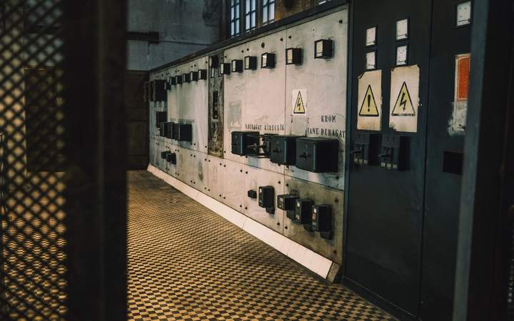 Couloir d’un local électrique bordé d’armoires de distribution et de panneaux de danger