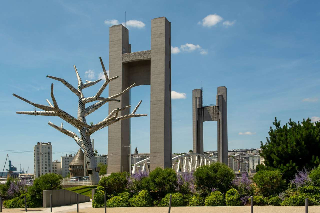 Les pylônes du pont de Recouvrance à Brest, avec une sculpture d’arbre en métal et une tour ancienne au premier plan