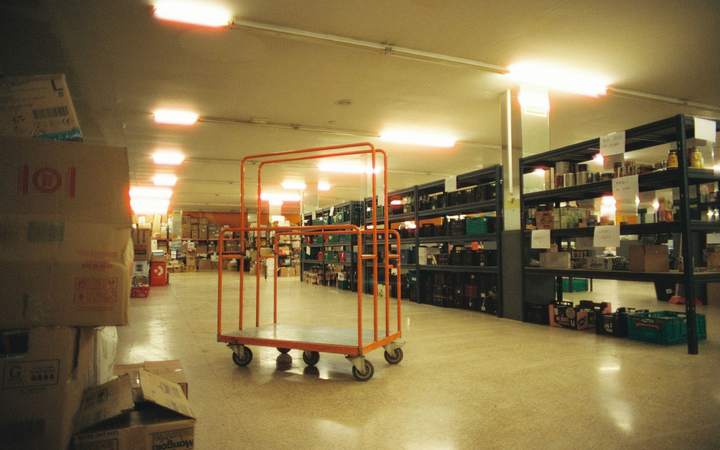 Réserve de stockage avec rayonnages métalliques, cartons et chariot roulant orange