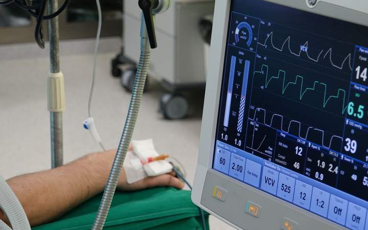Moniteur de surveillance affichant les constantes près du bras d’un patient perfusé