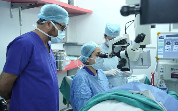 Équipe masquée opérant sous microscope chirurgical ophtalmique au bloc opératoire