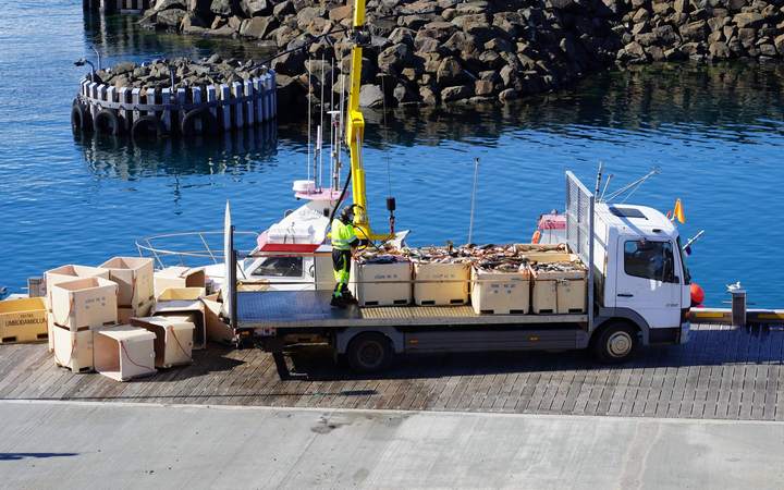 Camion chargé de caisses sur un quai de port de pêche pendant un déchargement à la grue