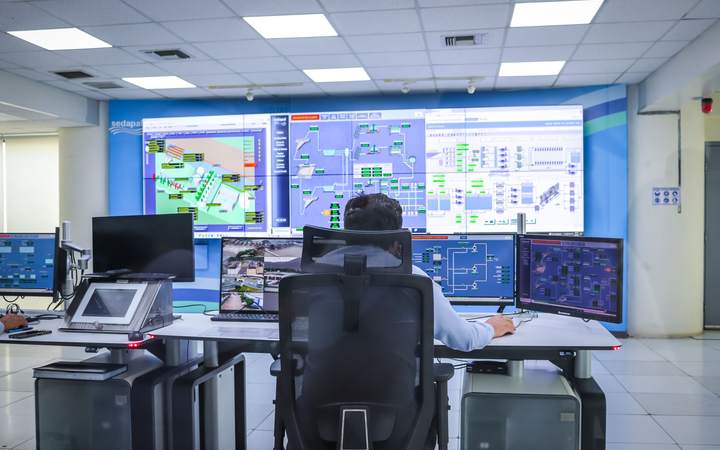 Opérateur de dos surveillant les écrans d’une salle de supervision d’installation technique